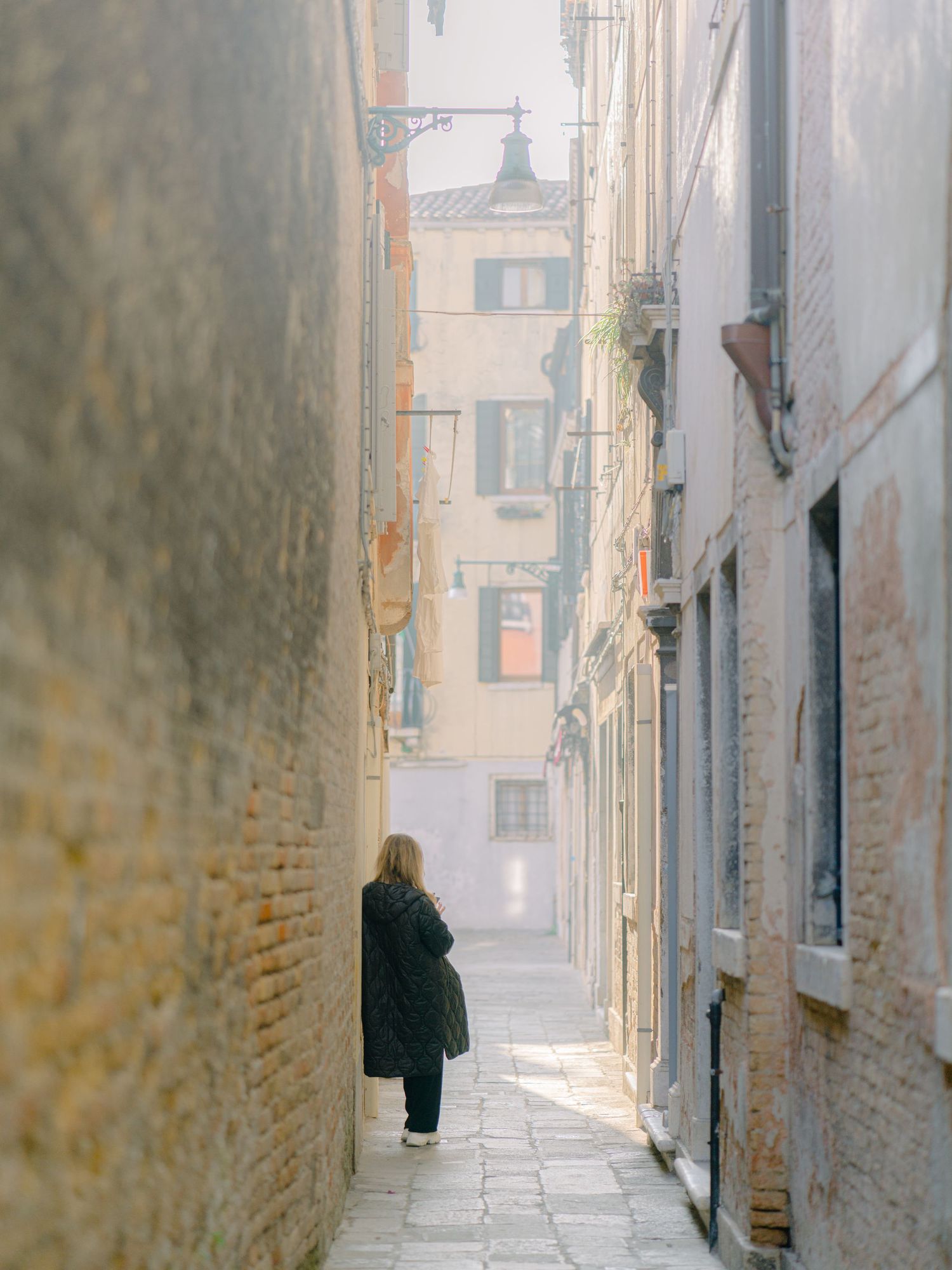 A young woman texting in a narrow street in Venice Italy