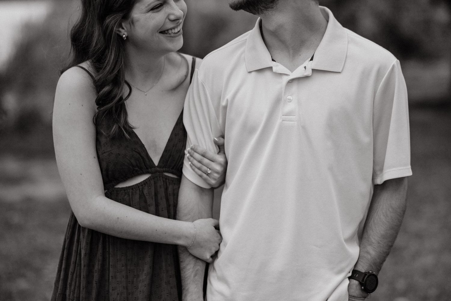 Black and white photo of smiling couple embracing outdoors.