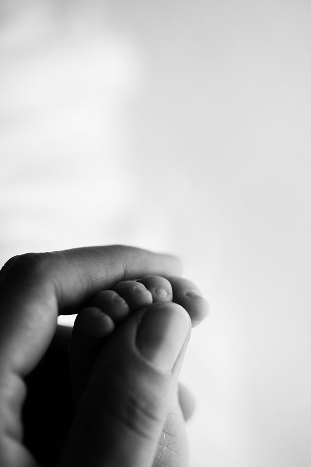 Newborn girls toes curled around mom's thumb.