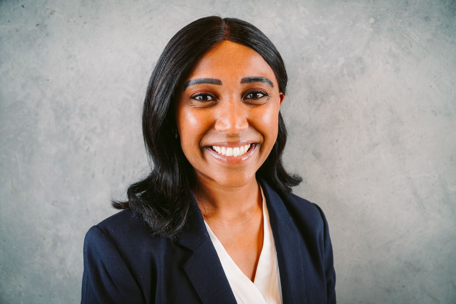 Professional headshot portrait of person in business suit against neutral background.