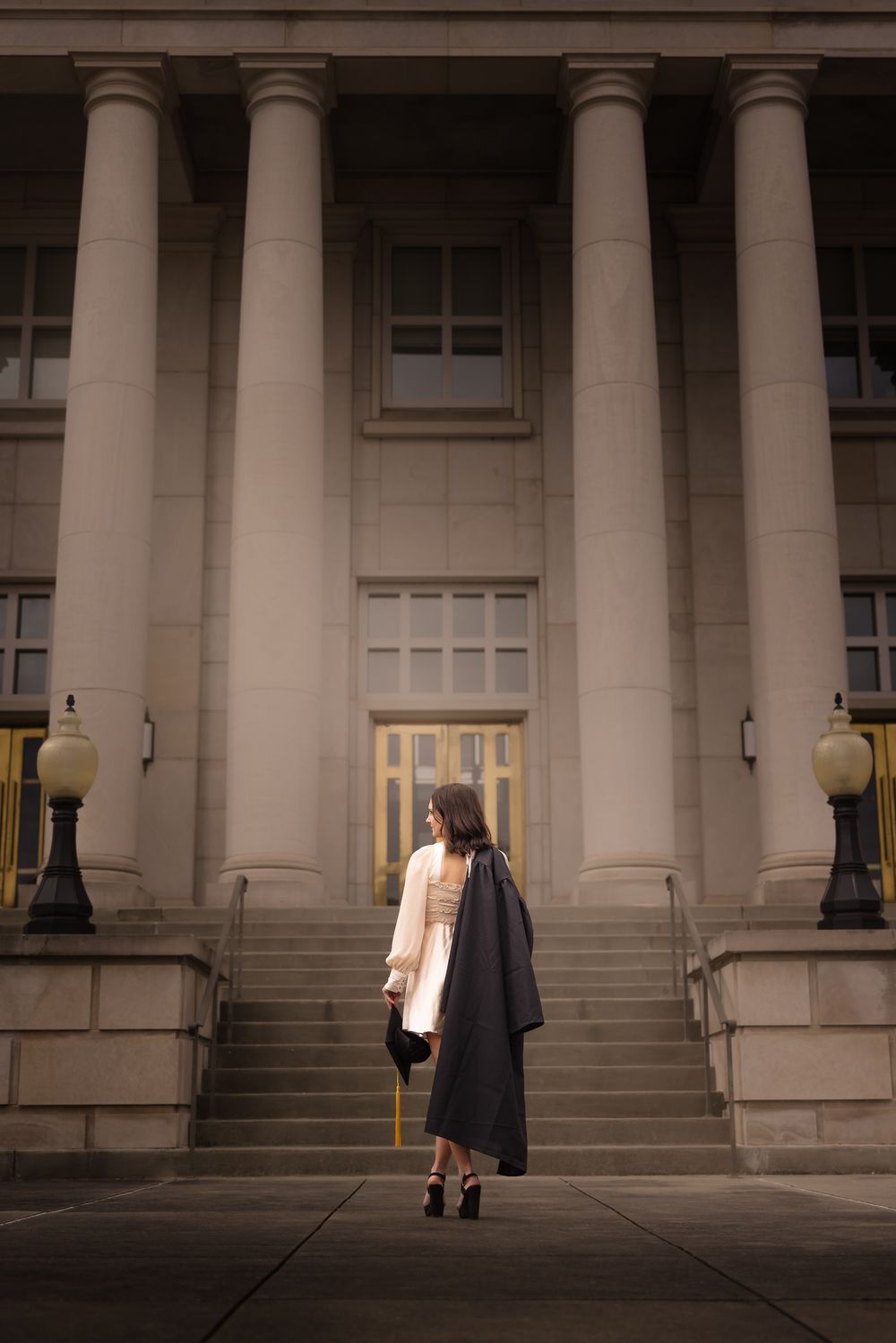 Architectural graduation photo showing graduate against grand pillared building facade.
