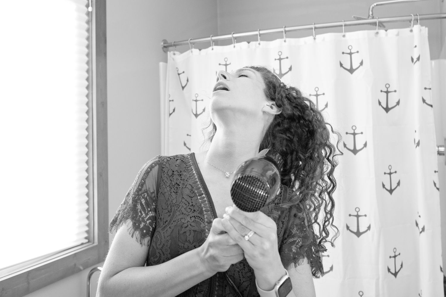 Candid moment of hair styling with natural window light and nautical decor.