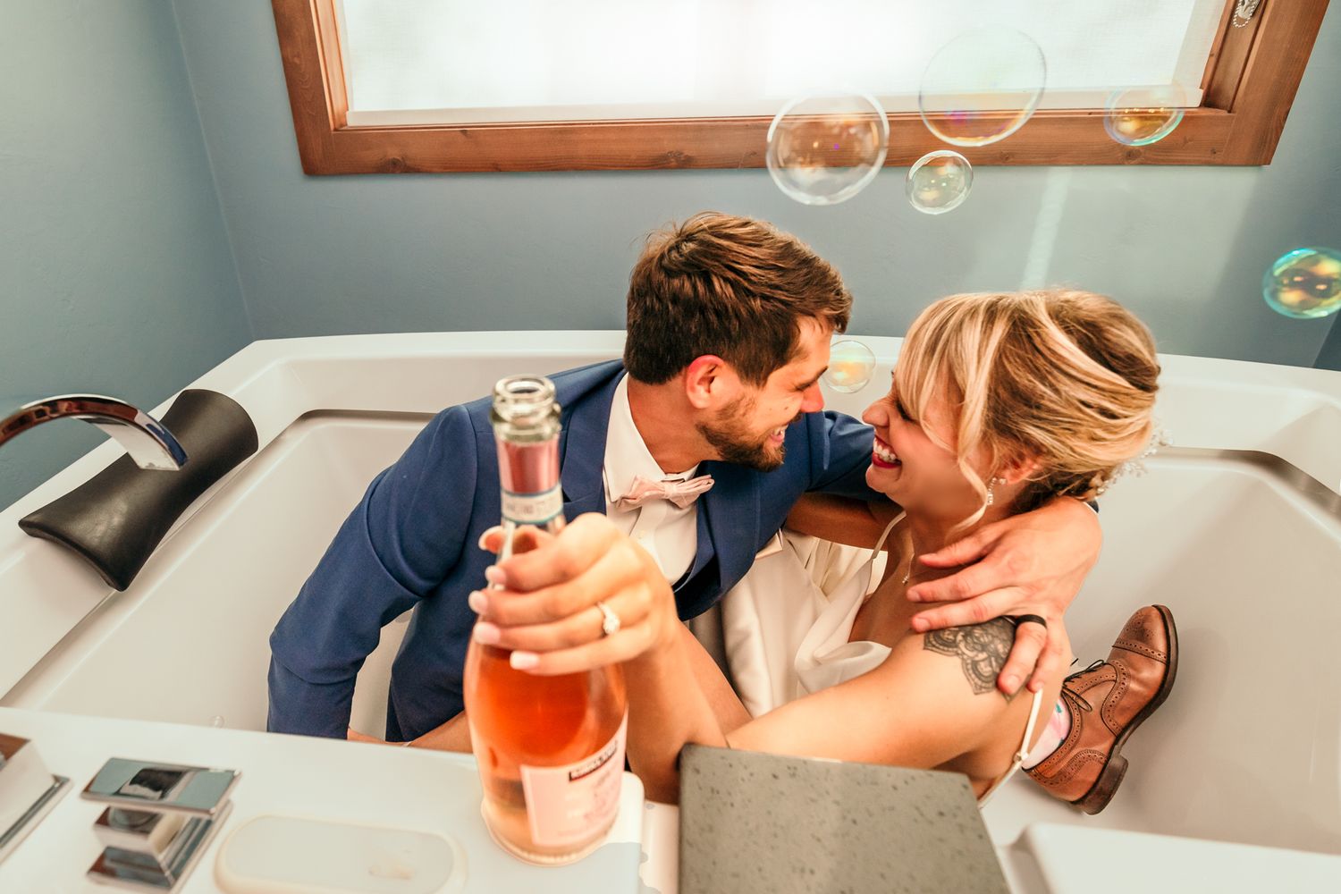 Romantic couple sharing drinks with floating bubbles by window.