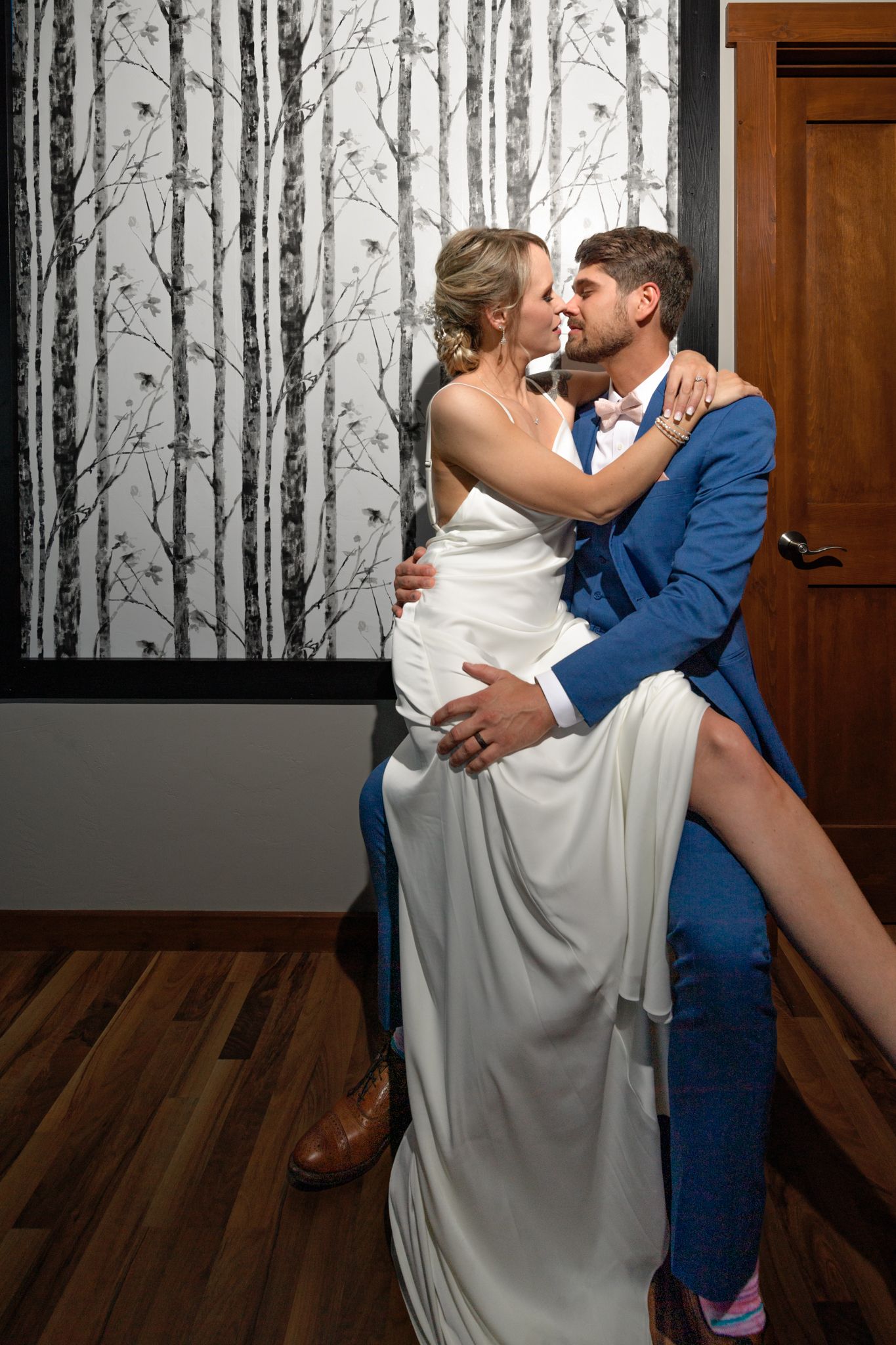 Wedding couple in elegant pose against birch tree wallpaper.