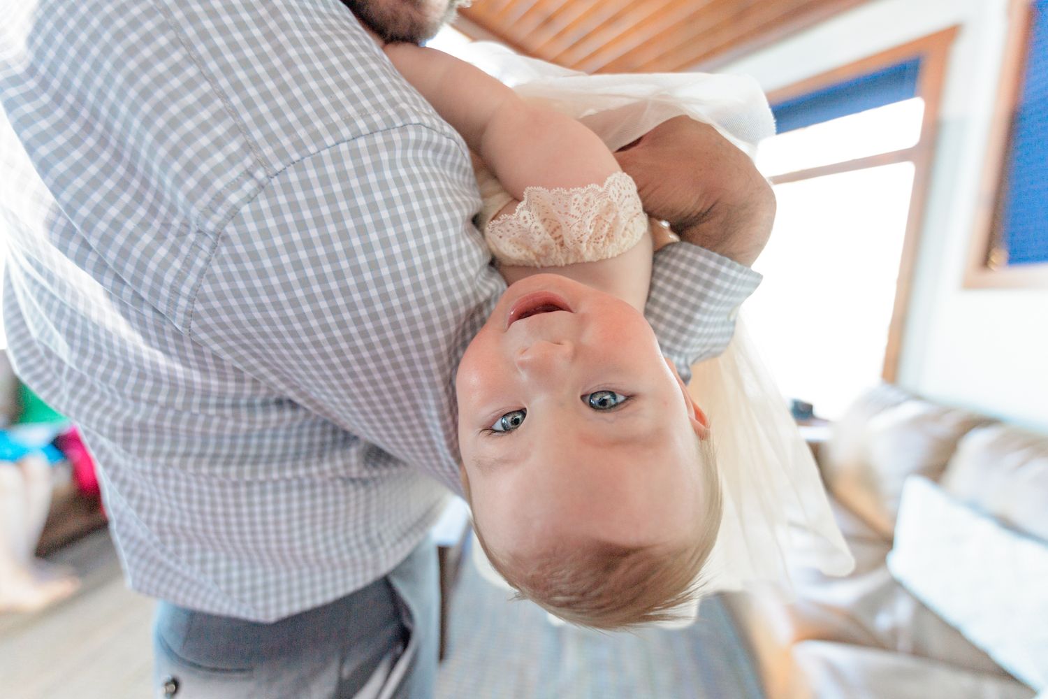 Upside down playful portrait in casual attire by window.
