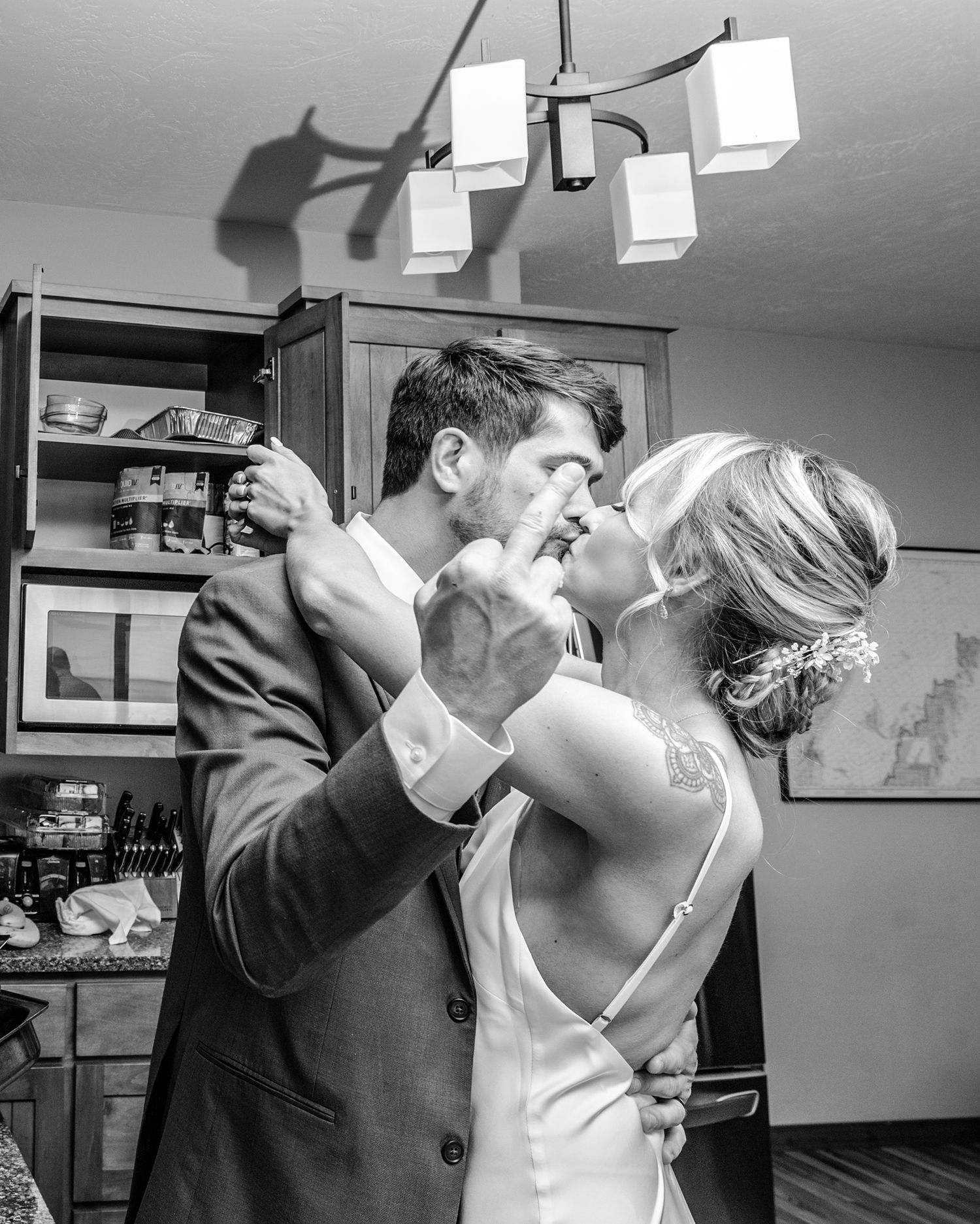 A couple shares an intimate moment in a kitchen with modern lighting fixtures.