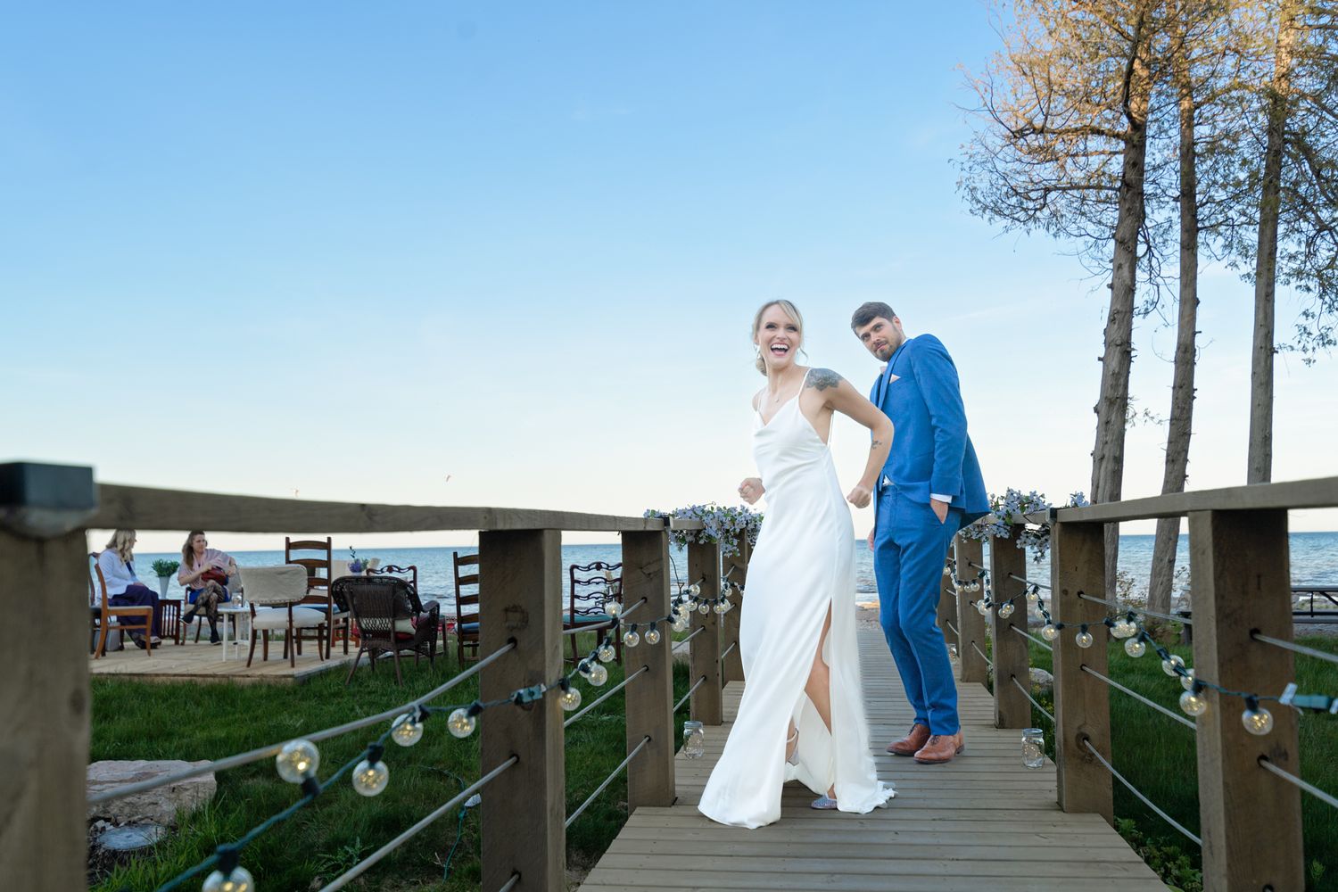 A couple walks along a decorated oceanfront boardwalk with string lights.