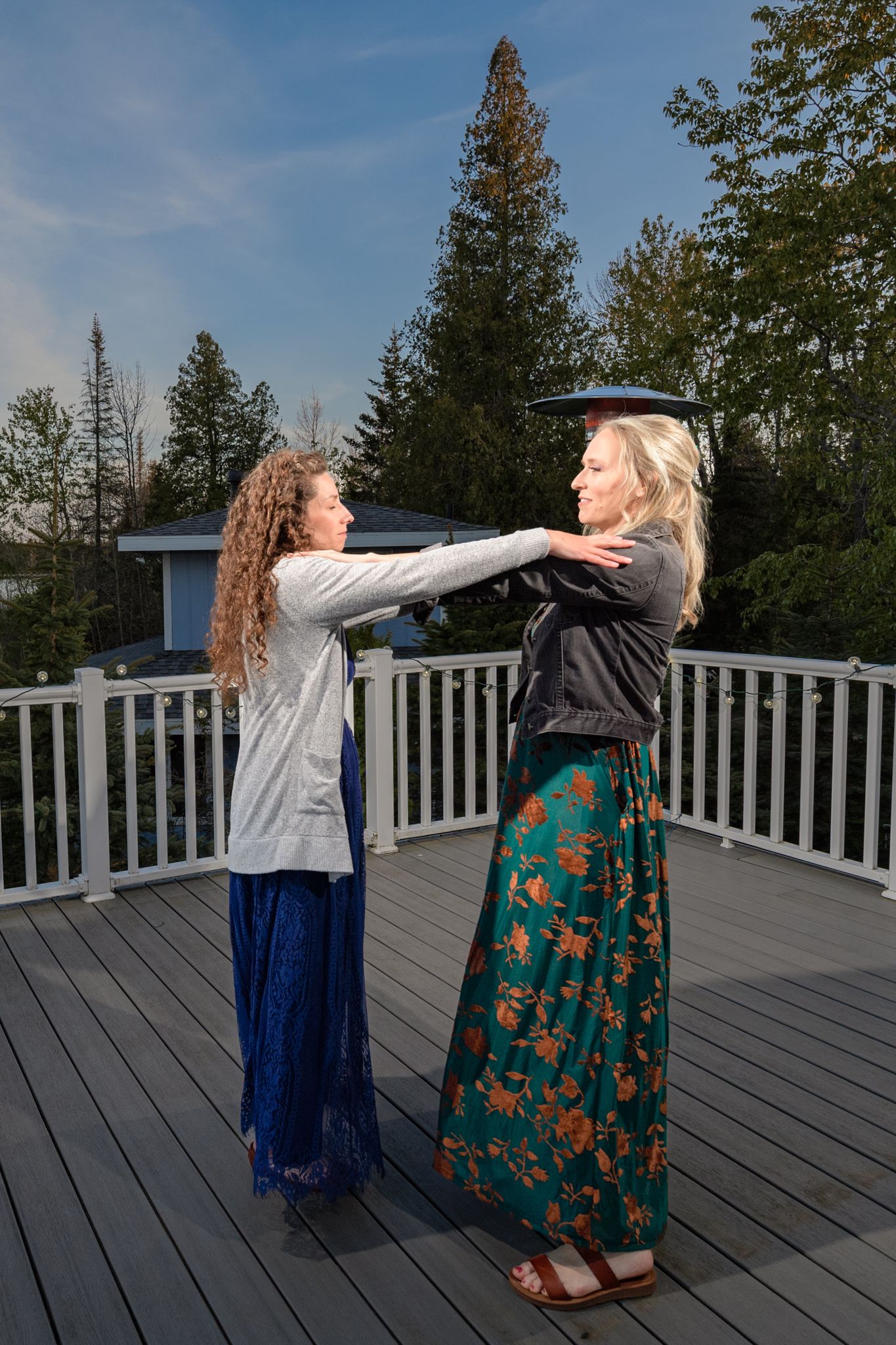 Two people dancing and laughing together on a wooden deck surrounded by pine trees.