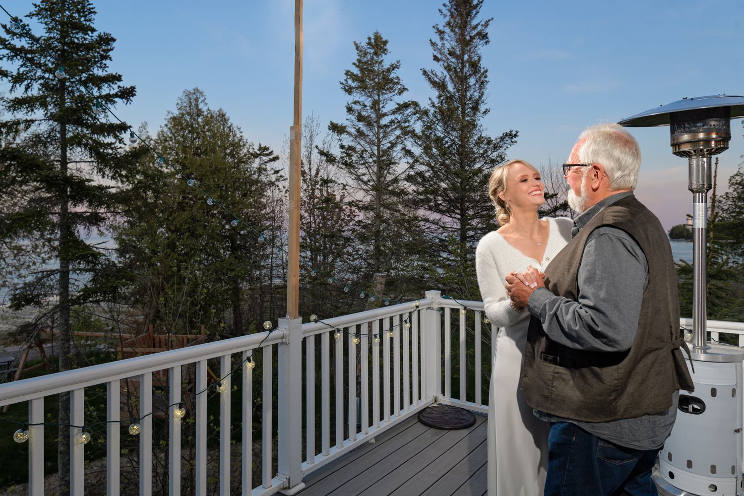 An intimate moment shared on a deck overlooking a scenic forest landscape at sunset.