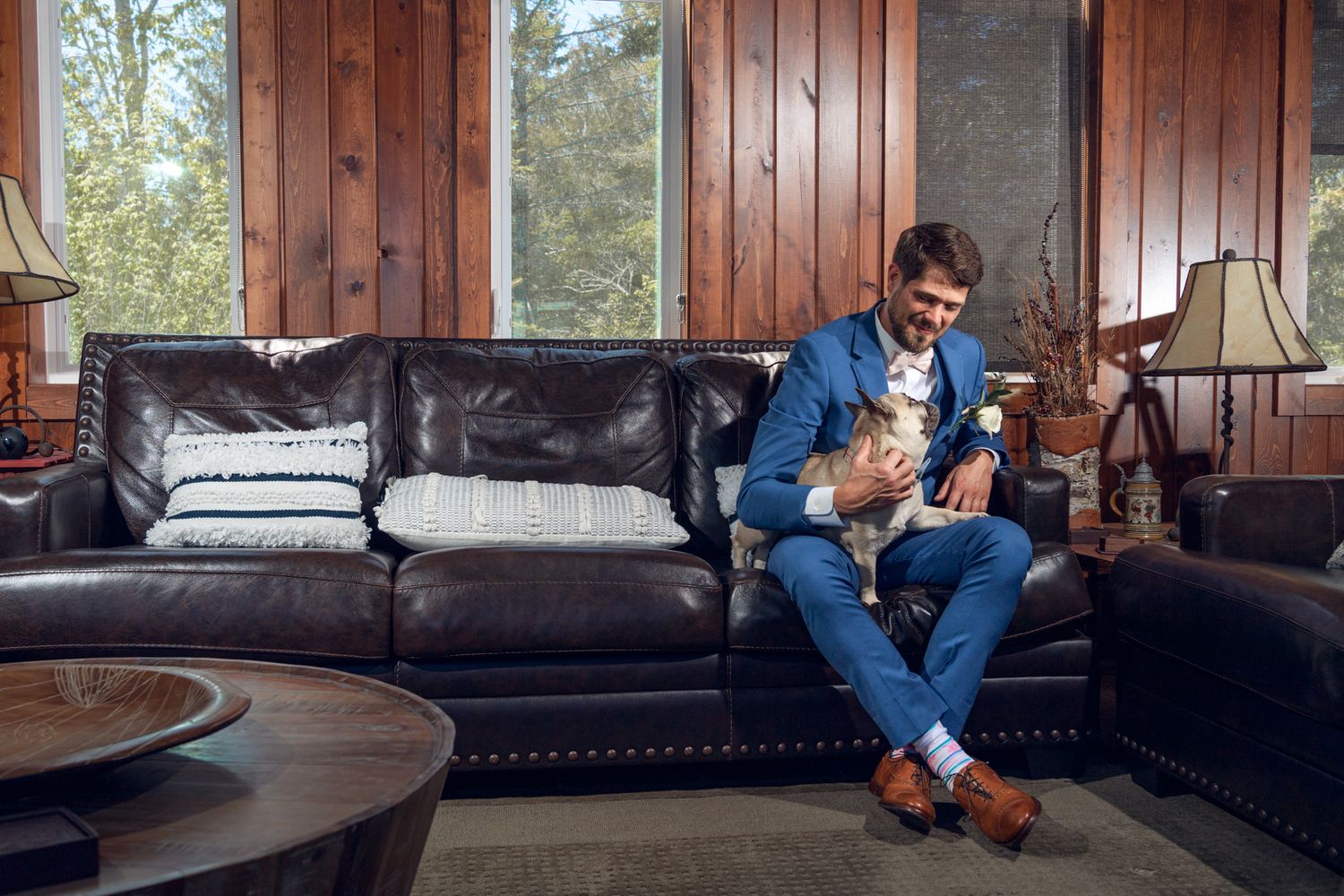 Person sitting on leather couch in rustic room with wooden wall panels.
