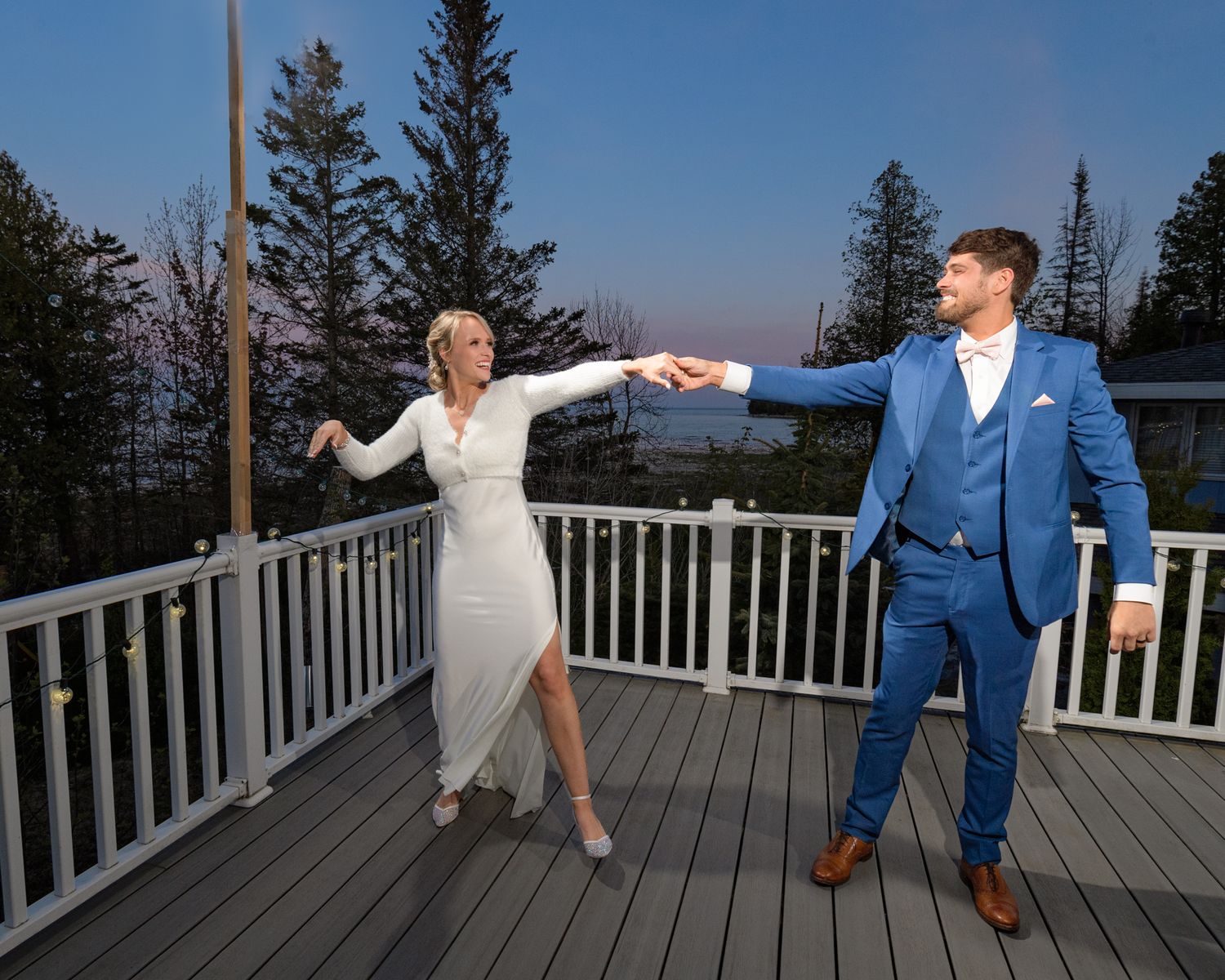 A playful dance sequence on an outdoor deck with elegant formal attire and mountain backdrop.
