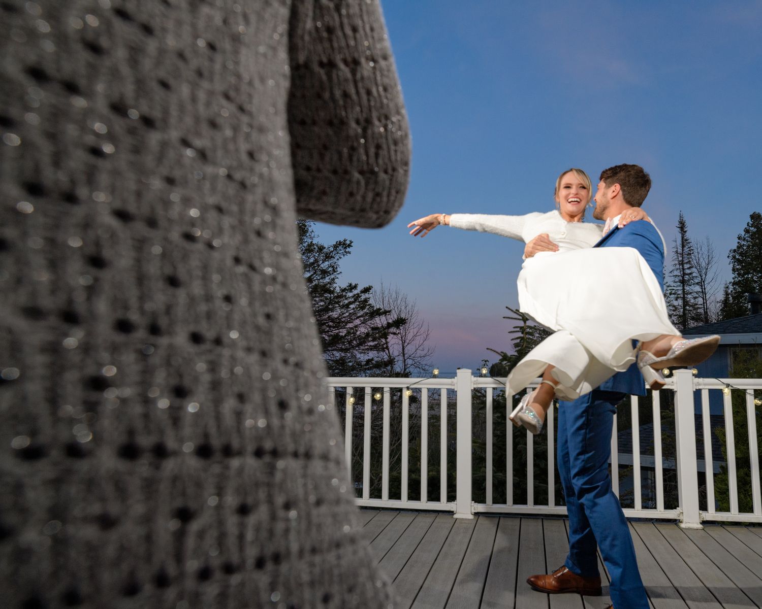 A whimsical lift dance pose photographed on a deck with pine forest backdrop.