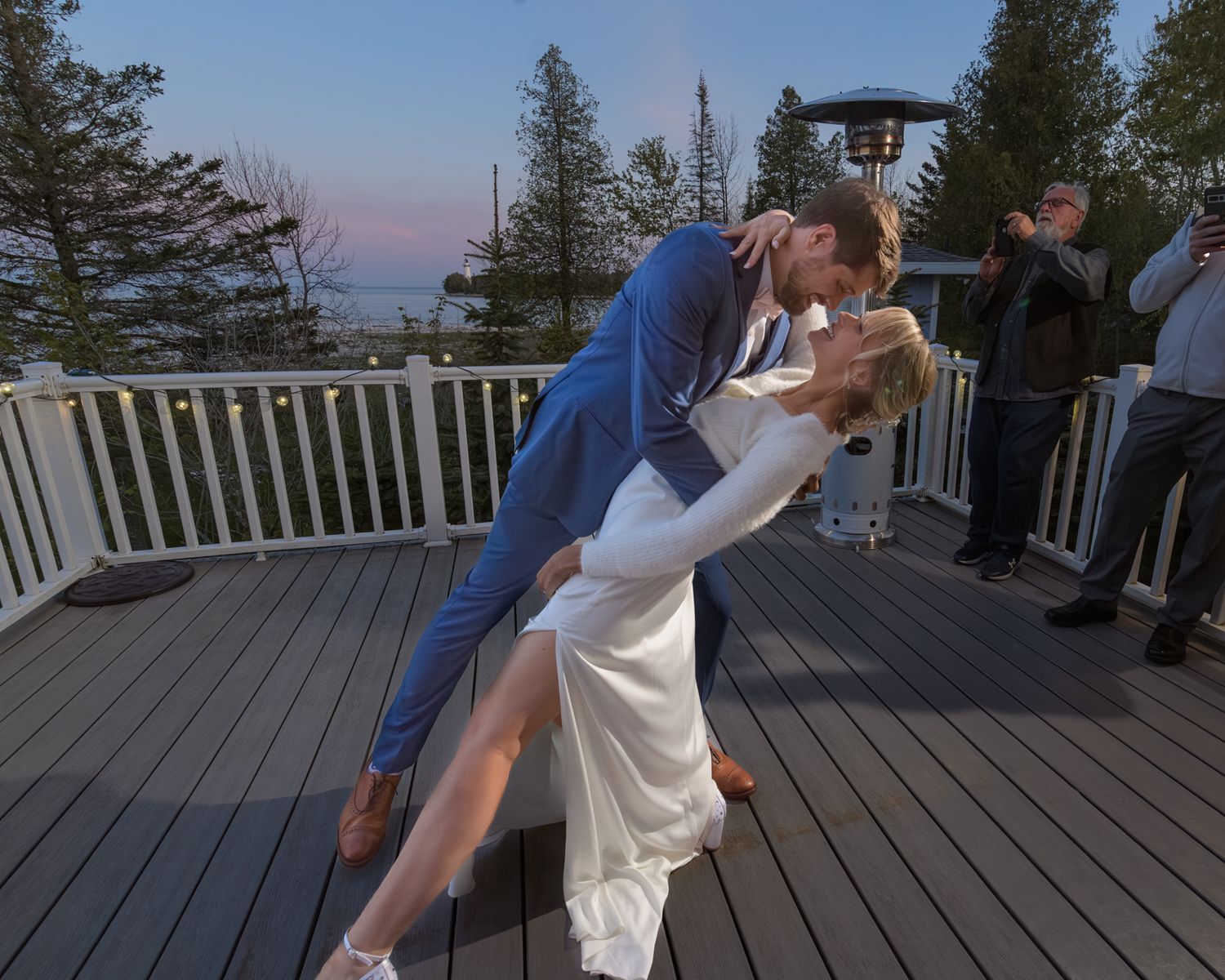 A romantic dip dance move performed on an outdoor deck with onlookers visible in background.