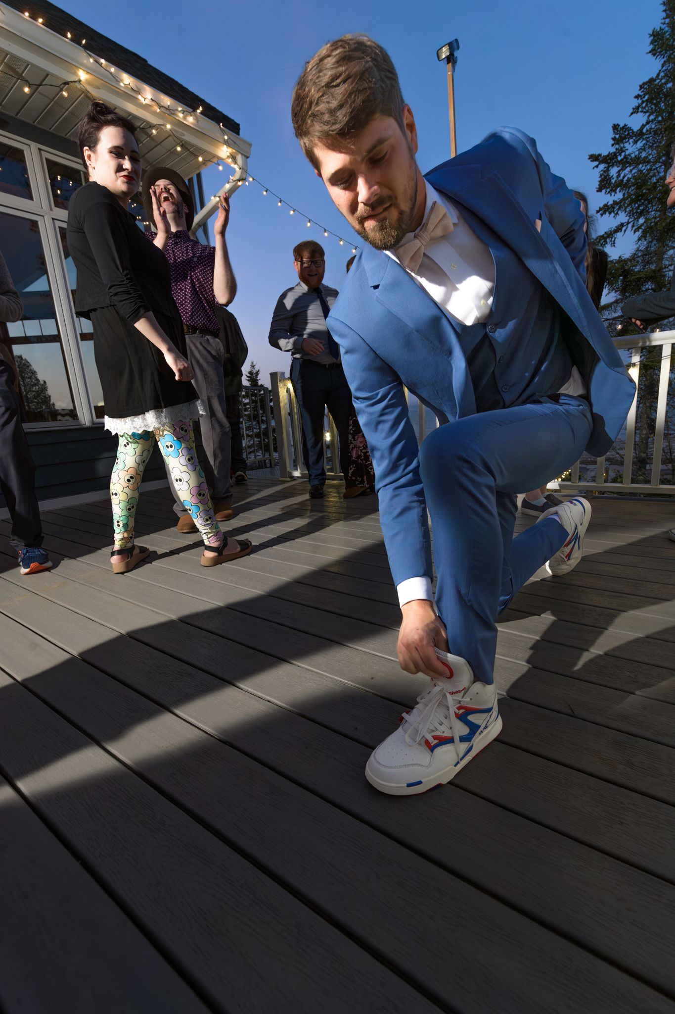 Person in blue suit showing off dance moves on outdoor deck during celebration.