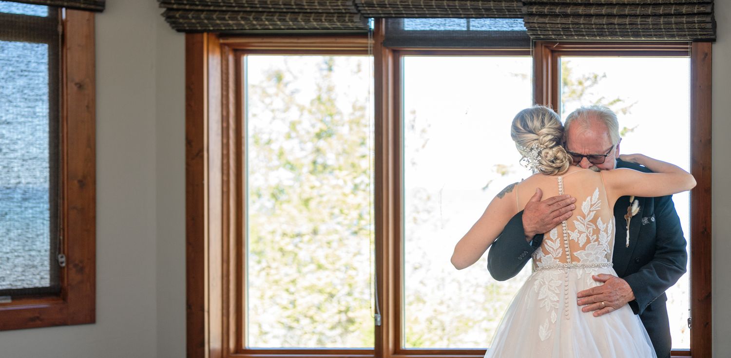 Emotional embrace captured in front of large windows with natural light streaming in.