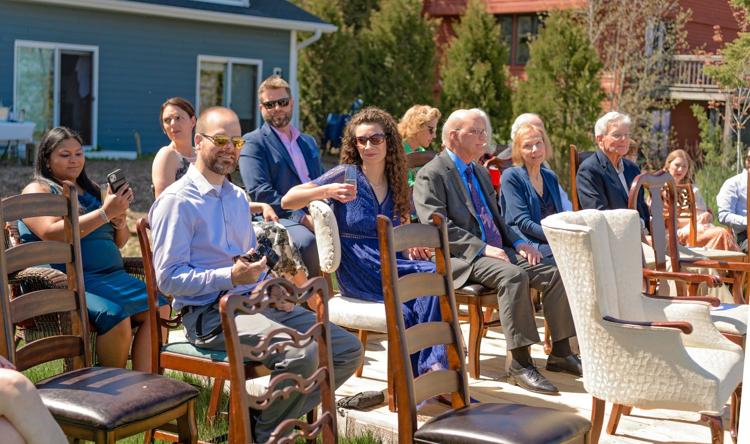 Outdoor wedding ceremony seating arrangement with wooden chairs on a lawn.