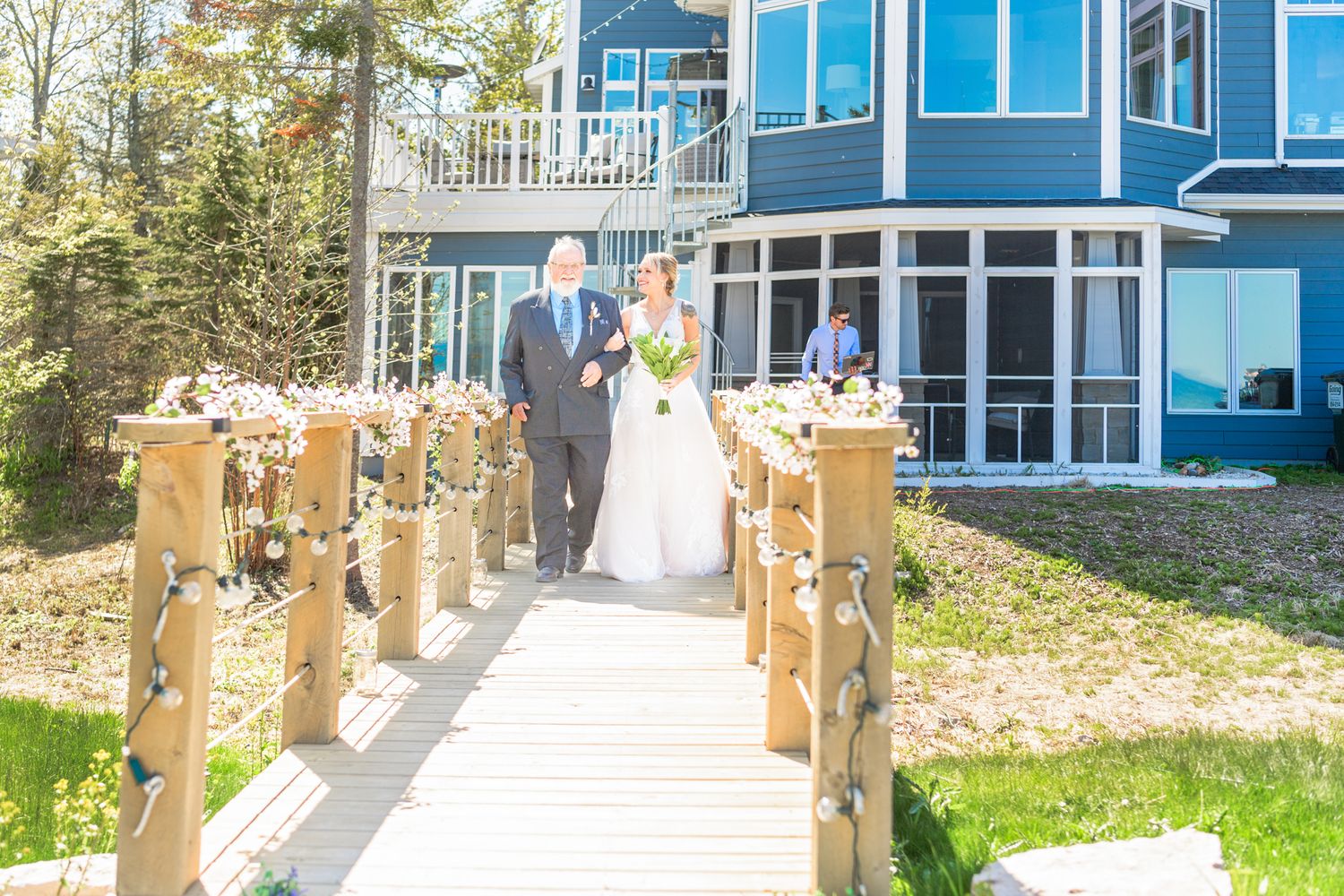 Decorated wooden boardwalk leading to modern blue house with white trim.