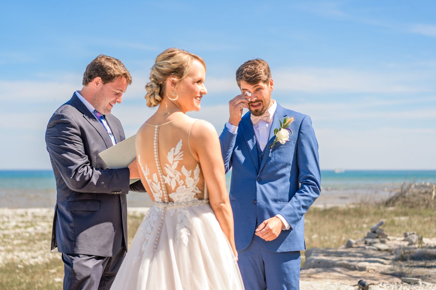 Wedding ceremony moment captured against coastal background on sunny day.