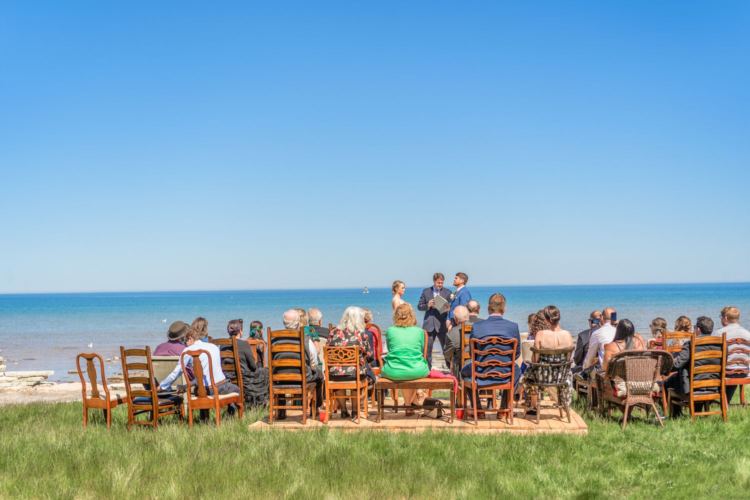 Outdoor wedding ceremony setup with wooden chairs facing the ocean view.