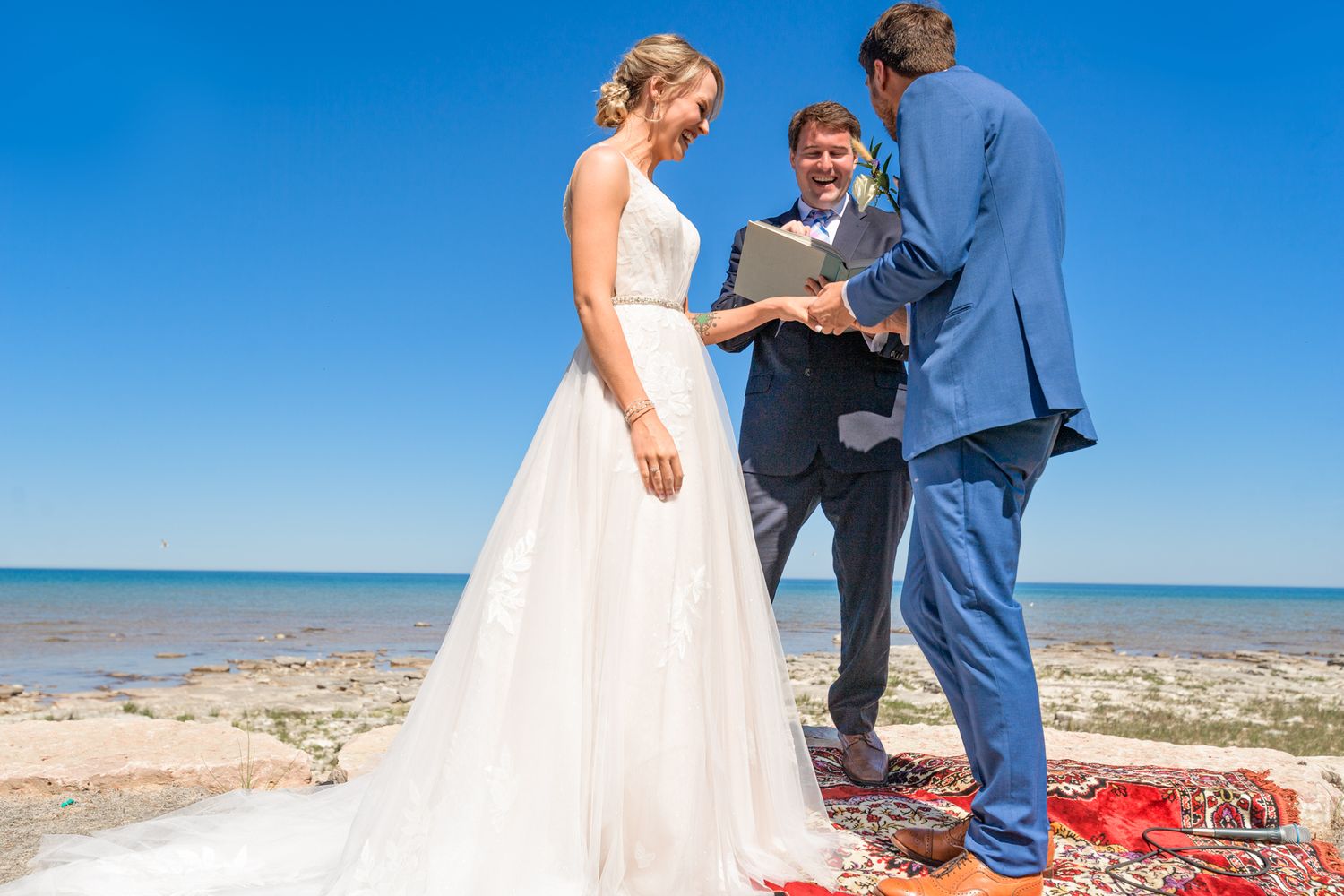 A coastal wedding ceremony on a red carpet with ocean views in the background.