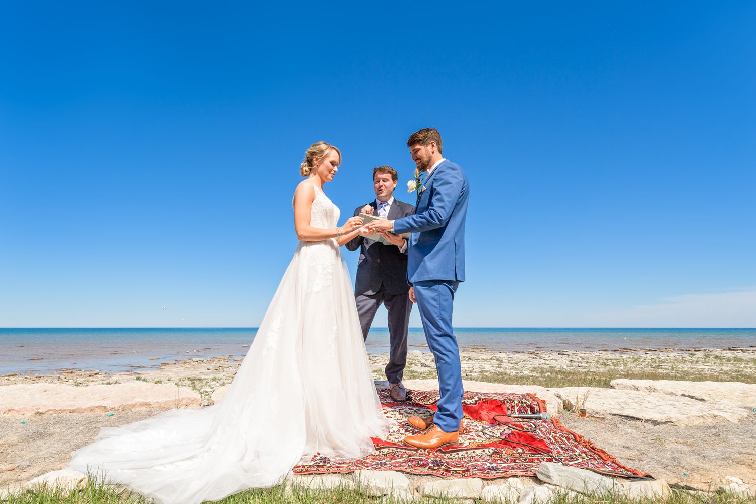 An outdoor wedding ceremony overlooking the water with guests seated on the lawn.