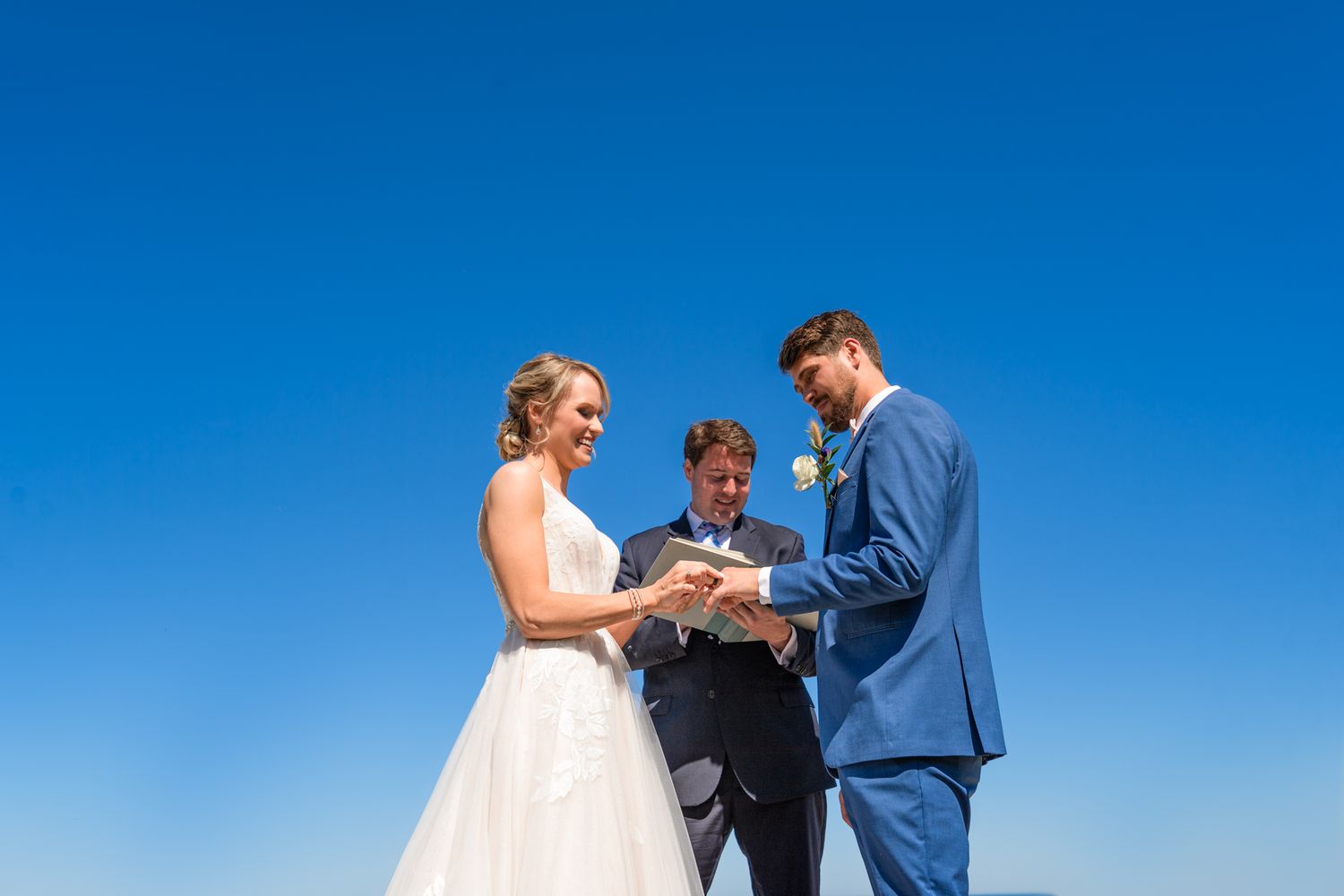 A seaside wedding ceremony with guests seated watching the proceedings.