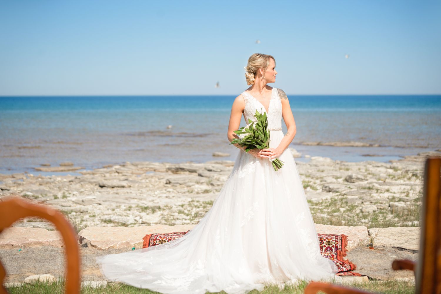 A beachside bridal portrait featuring a white gown and natural bouquet against the ocean.