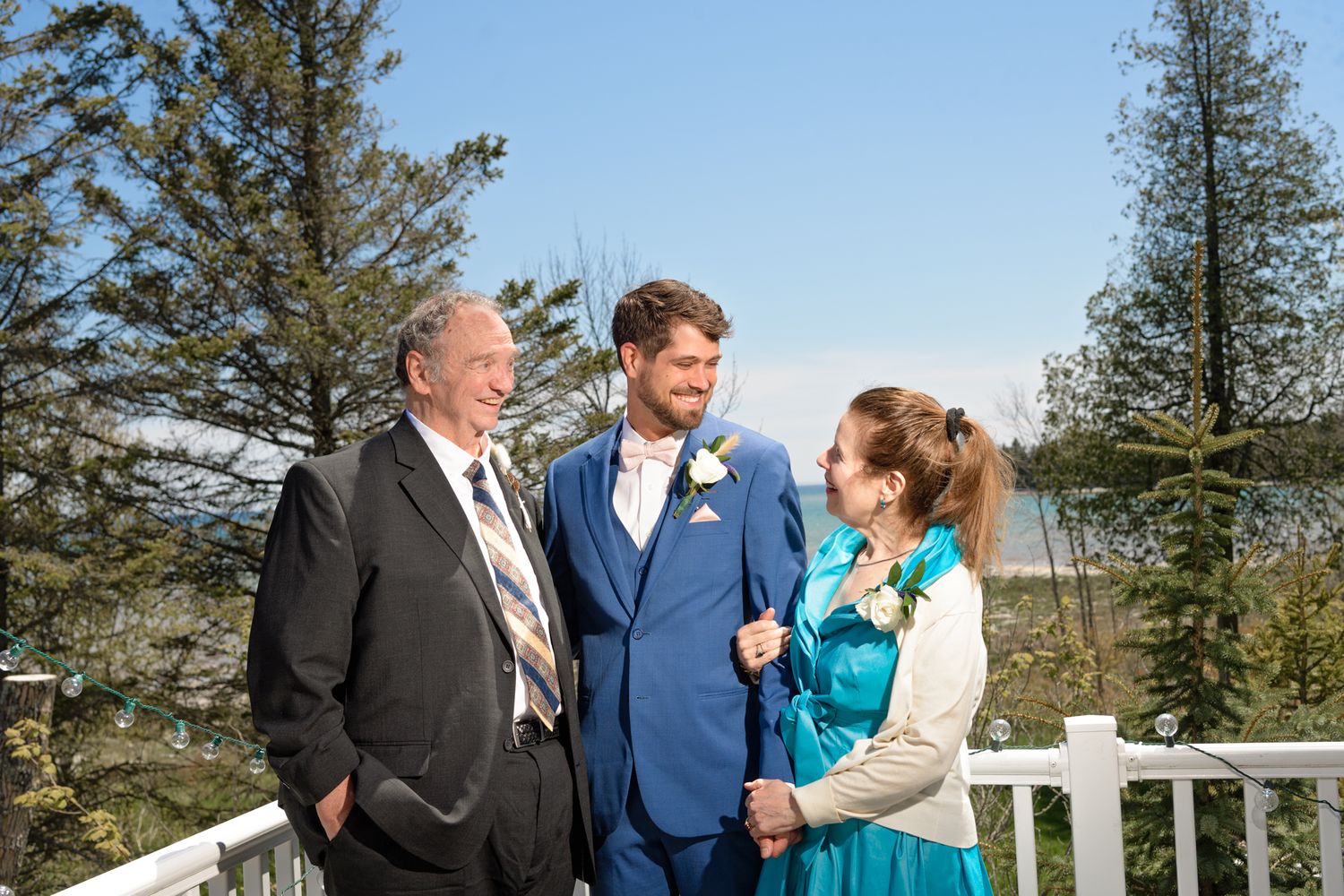 Group enjoying a sunny moment on an outdoor deck surrounded by evergreen trees.