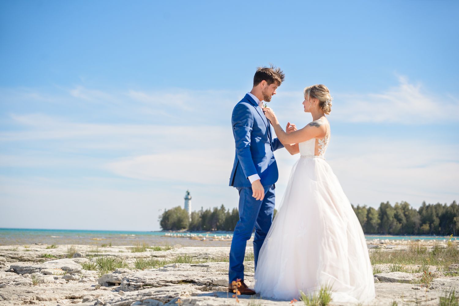 A tender wedding moment shared on a sunlit beach with ocean and lighthouse views.