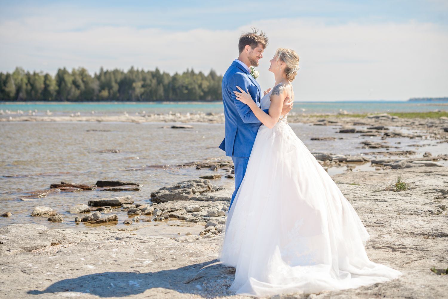 A romantic beach wedding portrait with waves crashing on rocky shores in the background.