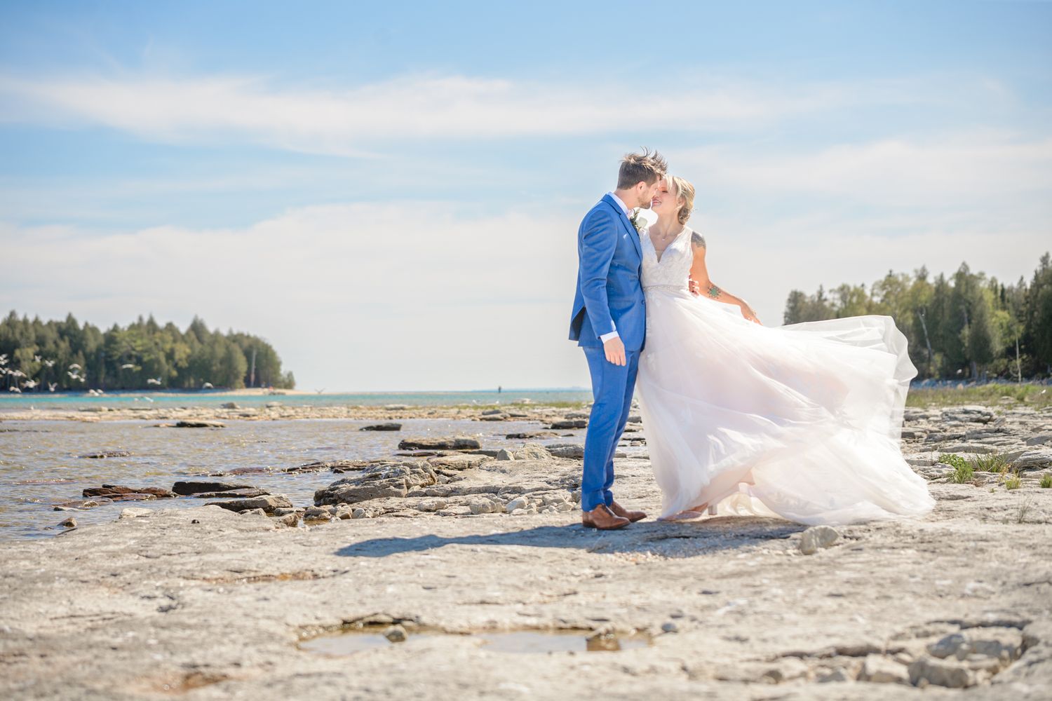 A romantic moment between newlyweds on a scenic rocky shoreline.