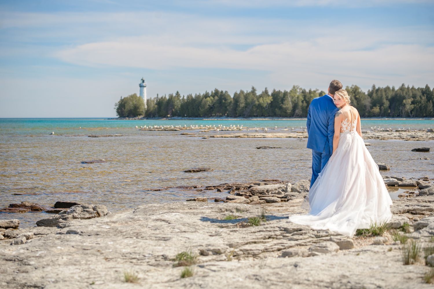 A couple enjoying a scenic coastal view with lighthouse in the distance.