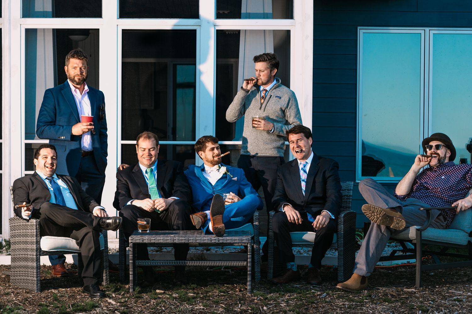 Groomsmen relax on outdoor furniture while enjoying pre-wedding celebrations.