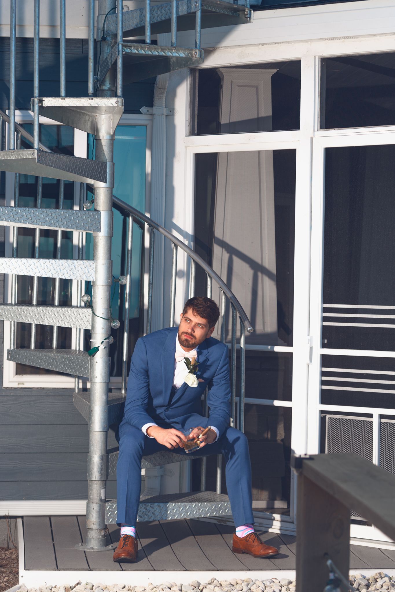A person in a blue suit sits thoughtfully on modern spiral staircase steps.
