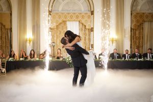 A couple performs their first dance in an elegant ballroom with sparklers and fog effects on a grand dance floor.