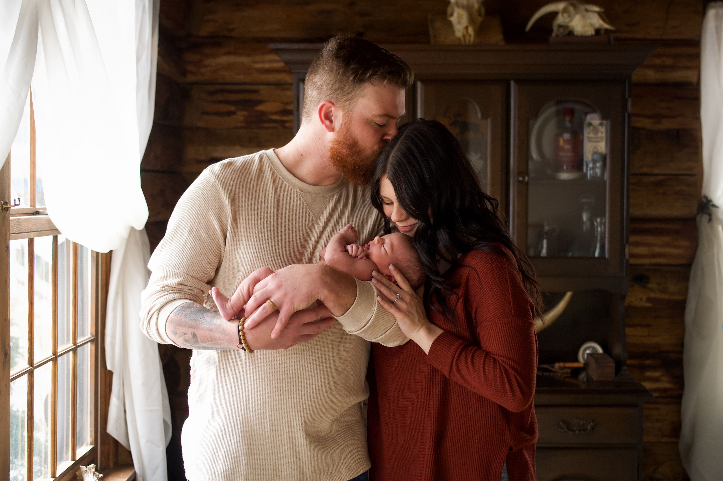 A couple shares a romantic moment in a rustic cabin setting with natural light streaming through windows.