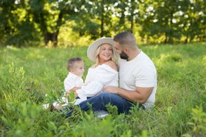 A sunny outdoor family portrait in a grassy field on a summer day.