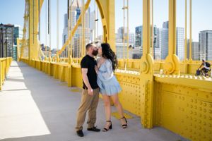 A romantic moment captured on a yellow bridge with city buildings in the background.