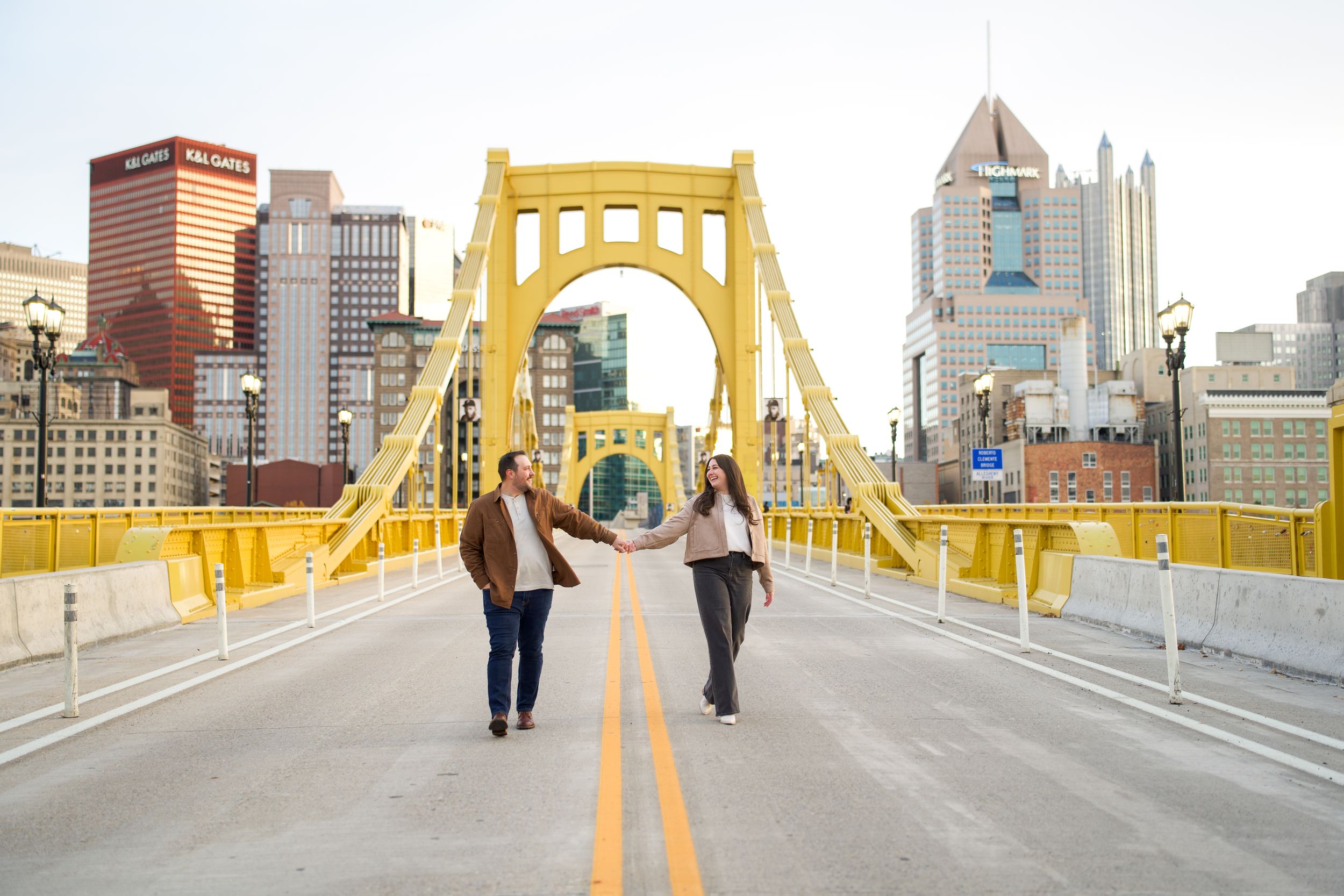 People walking across Pittsburgh's iconic yellow Roberto Clemente Bridge with the downtown skyline in the background.