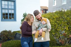 A family shares tender moments together while posing for outdoor portraits in casual attire.