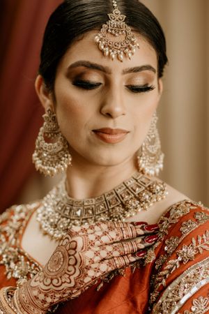Close-up of Indian bridal jewelry and makeup with traditional maang tikka headpiece.