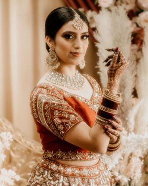 Indian bridal portrait featuring ornate jewelry and traditional red and gold attire.