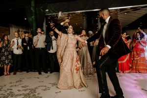 A couple dancing in coordinated moves at their reception while guests watch and cheer.