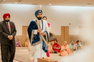 A Sikh ceremony taking place indoors with attendees in traditional dress.