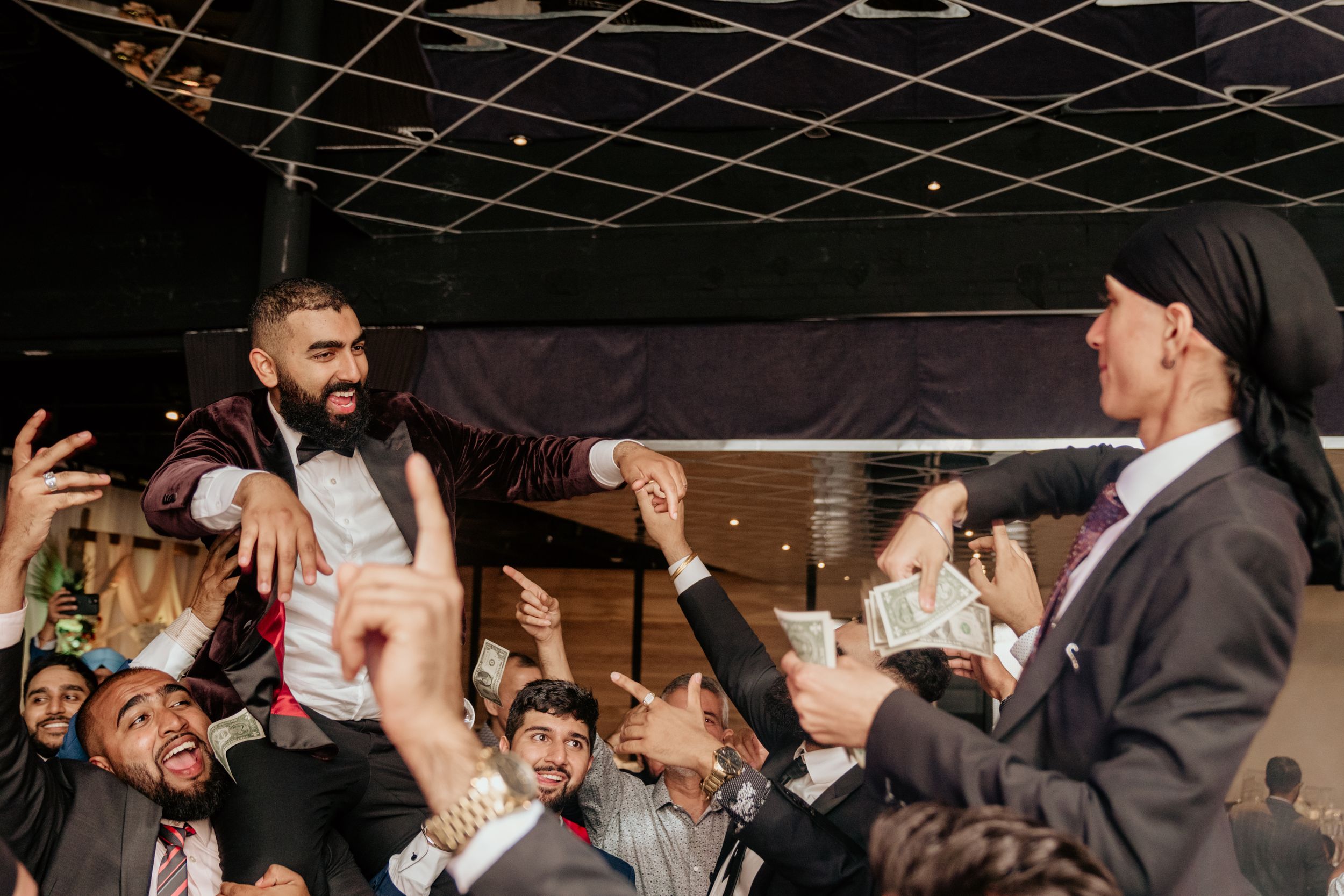 A celebratory moment at a wedding reception with people lifting someone up in excitement and joy.