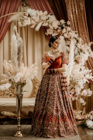 Full length shot of traditional Indian bridal outfit with floral arch decorations.