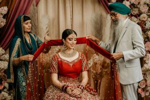 Traditional Sikh wedding ceremony with bride in red lehenga surrounded by family members.