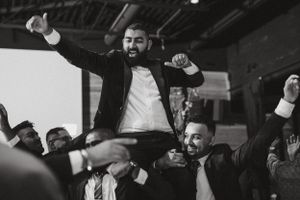 A celebratory moment as guests lift someone during an energetic wedding reception dance party.