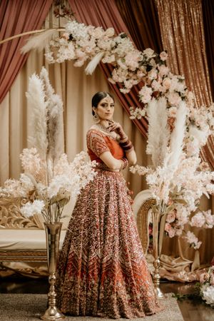 Full-length Indian bridal portrait with white floral decor and traditional lehenga.