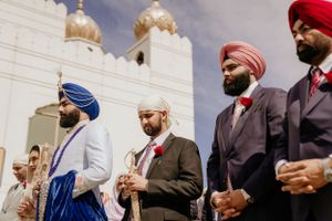 Men in turbans and formal attire stand together during a traditional Sikh ceremony.